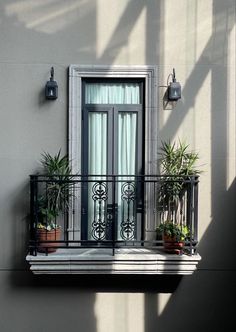 a balcony with potted plants on the windowsill and an open door to another room