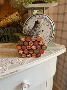 a clock sitting on top of a white dresser next to plants and other things in the background