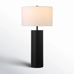 a black table lamp with a white shade on the base and a light in front of it