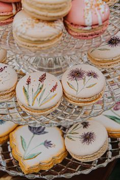 some cookies and pastries are sitting on a glass platter with flowers painted on them