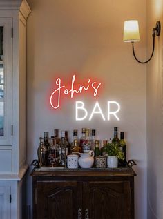 john's bar neon sign on the wall behind a bar with liquor bottles and glasses