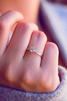 a woman's hand with a diamond ring on top of her finger and the other hand