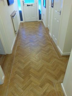 an empty hallway with wooden floors and white doors