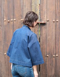 a woman standing in front of a wooden door with her back turned to the camera