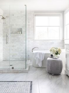 a white bathroom with marble flooring and walls