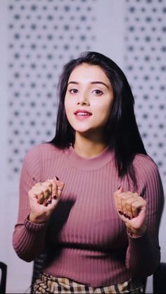 a woman in a pink sweater is holding her hands together