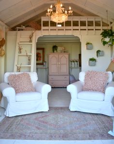 two white chairs sitting next to each other on top of a rug in a living room