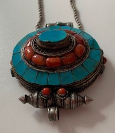 Tibetan Silver necklace with a big pendant deco with coral and turquoise ( i do not know how to open ). About prayer boxes: Traditionally, prayer boxes are used by Tibetans as portable shrines where prayers and sacred relics are kept. These prayer boxes marry that traditional concept with the Tibetan fascination for beautiful Jewelry. Tibetans write their wishes and prayers on a piece of paper and put it into the prayer box which they wear daily. By so doing, they believe that their godliness wi Traditional Turquoise Necklace With Inlay For Gift, Traditional Turquoise Inlay Necklace As Gift, Traditional Turquoise Necklace With Large Pendant As Gift, Traditional Turquoise Necklace With Large Pendant, Handmade Turquoise Medallion Necklace As Gift, Handmade Turquoise Medallion Necklace Gift, Handmade Turquoise Medallion Necklace For Gifts, Traditional Turquoise Pendant Necklace, Traditional Round Turquoise Necklace For Gift