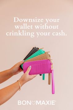 a woman's hand holding a pink purse with four different colored wallets in it