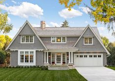 a large gray house with white trim and two story windows on the front of it