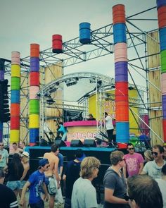 a large group of people standing in front of a stage with colorful columns on it