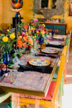 the table is set with colorful flowers and place settings for four people to sit at