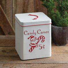 a candy cane box sitting on top of a wooden table next to a potted plant