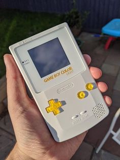 a person holding an old gameboy in their hand