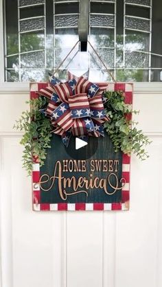 an american flag wreath hanging on a door with the words home sweet america painted on it