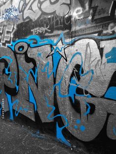 graffiti on the side of a wall with blue and black spray painted letters in it