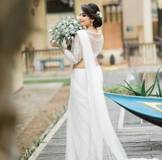 a woman in a white wedding dress standing next to a boat with flowers on it