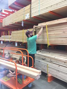 a man standing in front of stacks of wooden planks