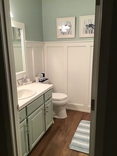 a white toilet sitting next to a bathroom sink in a room with blue walls and wooden floors