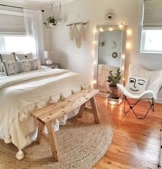 a bed room with a neatly made bed next to a mirror and lights on the wall