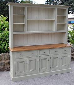 an old china cabinet with wooden top and drawers in front of some bushes on the sidewalk