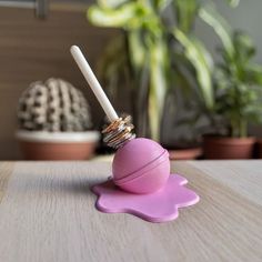 a pink object sitting on top of a wooden table next to a potted plant