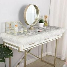 a vanity table with a mirror and plant on it