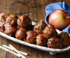 meatballs and apples on a wooden table with toothpicks in the foreground