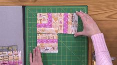 a person cutting up fabric on top of a green cutting board next to a pair of scissors