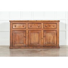 an old wooden sideboard with drawers and knobs on the doors is shown in front of a white wall