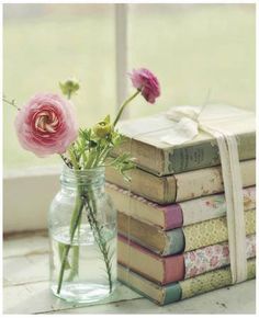 a vase filled with pink flowers next to books