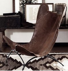 a brown leather chair sitting on top of a rug next to a wooden table and mirror