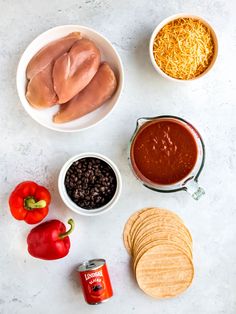 ingredients to make mexican chicken dip laid out on a white counter top, including tortilla chips and salsa