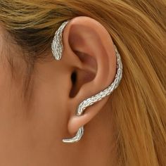 a woman's ear is shown with two silver snakes on it