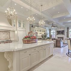 a large kitchen with white cabinets and chandeliers hanging from the ceiling above it