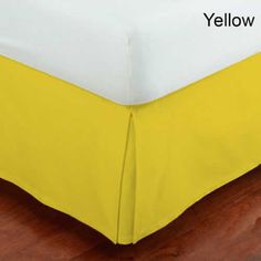 a yellow and white bed skirt sitting on top of a wooden floor