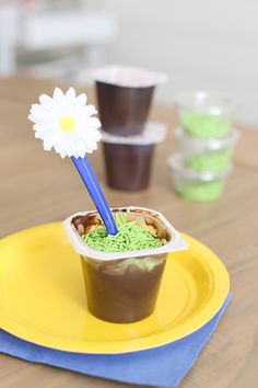 a plastic cup filled with green sprinkles and a flower sticking out of it