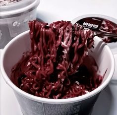 a bowl filled with lots of red food next to two plastic containers full of ice cream