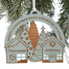 a christmas ornament hanging from a tree with a house and trees on it