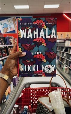 a person is holding up a book in a store with the words wahala on it