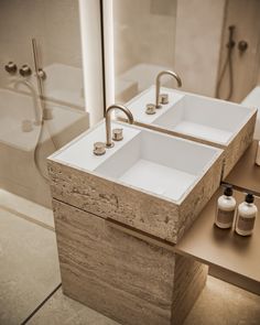 two white sinks sitting next to each other on top of a wooden counter in a bathroom