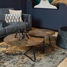 two tables sitting on top of a rug in front of a gray couch and chair