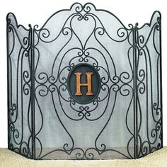 an iron fireplace screen with the letter h on it