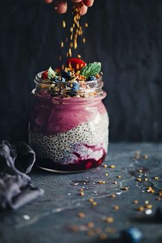 someone sprinkling seeds into a jar filled with food