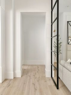 an empty room with white walls and wood flooring is seen from the hallway to the living room