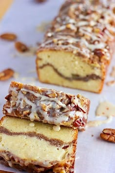 two pieces of cake sitting on top of a piece of wax paper next to pecans