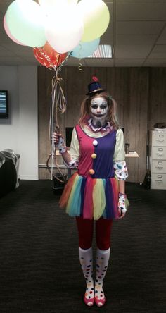 a woman dressed as a clown with balloons in her hand and makeup painted to look like a skeleton