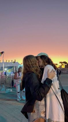 two women standing next to each other in front of a crowd at sunset or sunrise