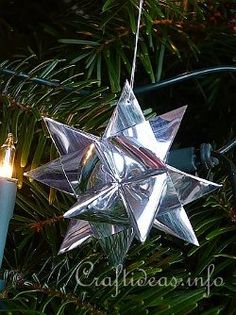 a silver star ornament hanging from a christmas tree next to a lit candle