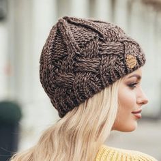 a woman with blonde hair wearing a brown knitted hat and looking off to the side